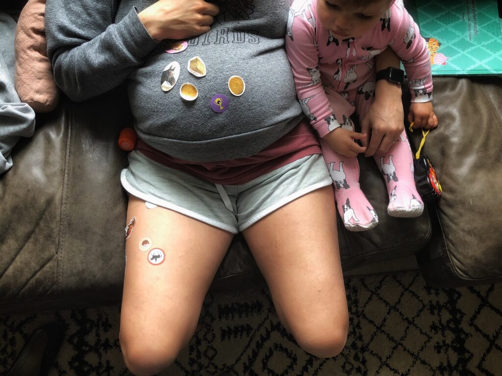 Pregnant belly during covid with stickers on it.