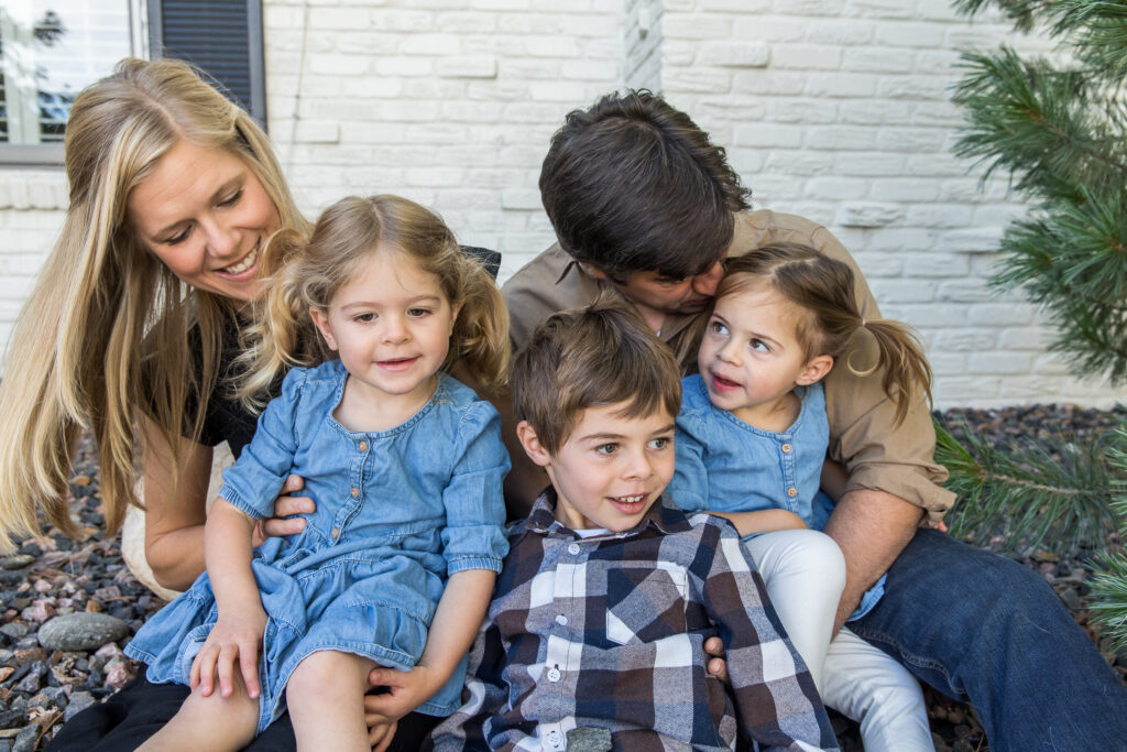 Family of five snuggling in front yard during photo session at their home in Denver Colorado.